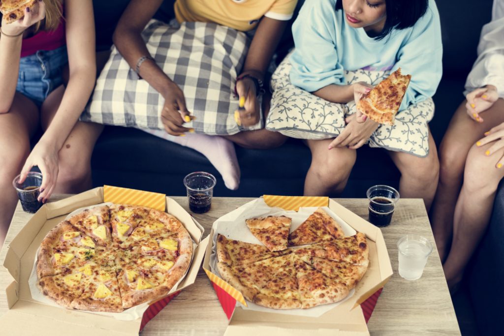 ragazze mangiano pizza sul divano