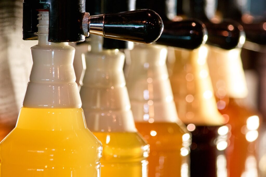 Diversi tipi di versamento della birra birre schiumose di diversi tipi sui rubinetti della birra.
