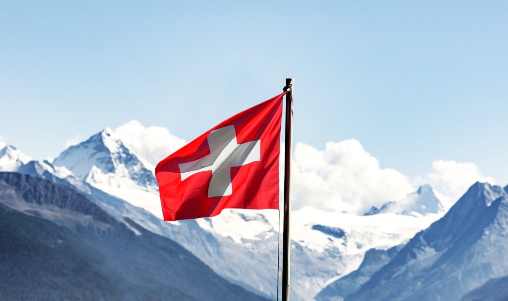 Bandiera svizzera con montagne e cielo blu sullo sfondo